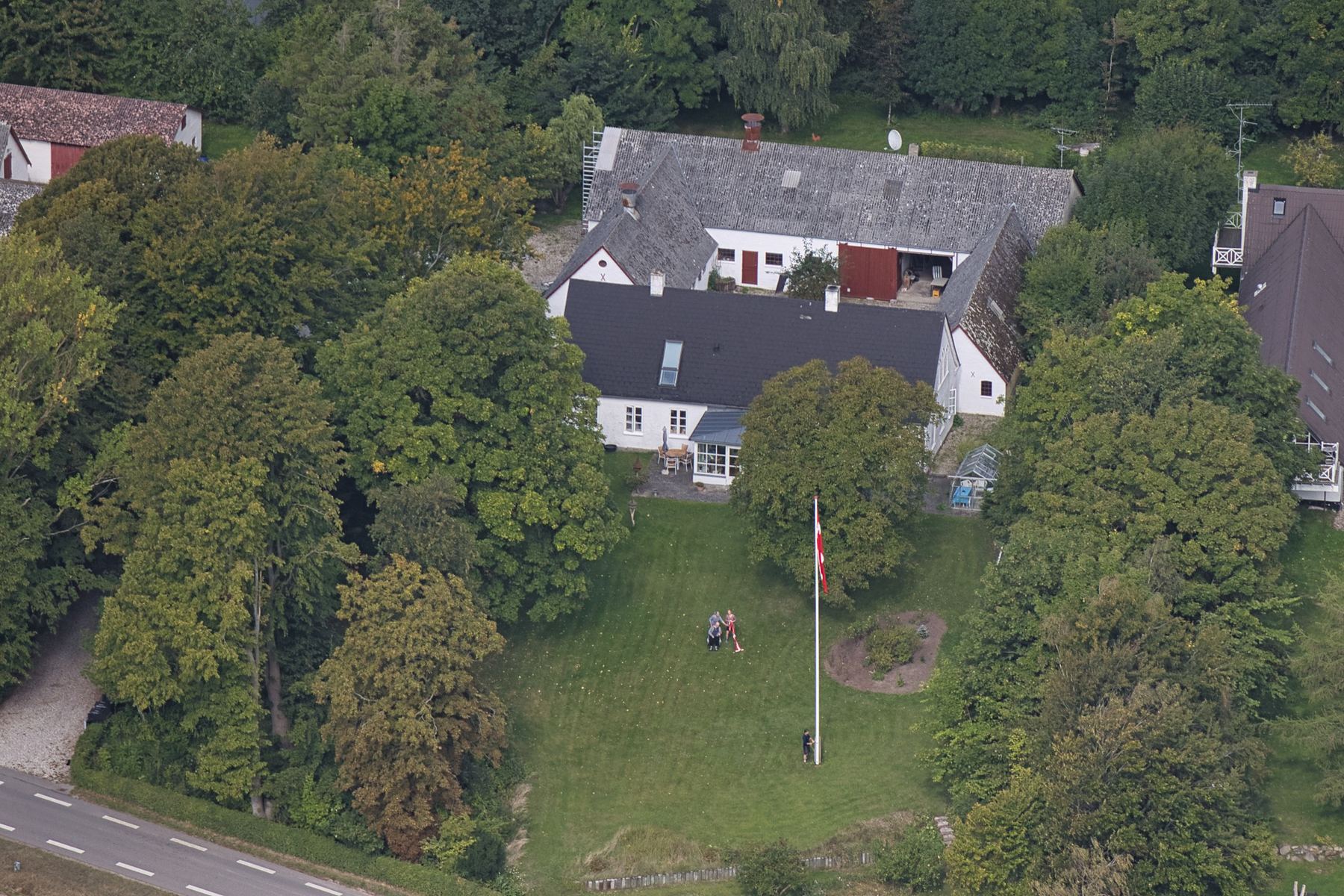 Hvidt hus med have og flagstang set fra luften